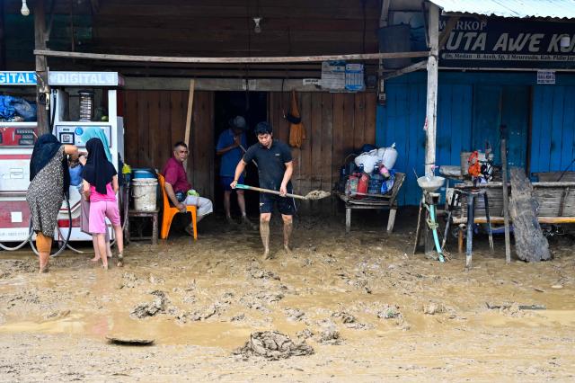 People clear mud from a building entrance following flash floods in Meureudu, Pidie Jaya district in Indonesia's Aceh province on November 28, 2025. Days of devastating flooding across Southeast Asia have killed more than 300 people in Indonesia, Thailand and Malaysia, authorities said on November 28. (Photo by CHAIDEER MAHYUDDIN / AFP)