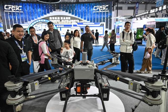 People visit the DJI booth during the Aero Asia 2025 in Zhuhai, in southern China's Guangdong province on November 29, 2025. Aero Asia 2025 is an international aviation and aerospace exhibition that runs between November 27 and 30. (Photo by Hector RETAMAL / AFP)