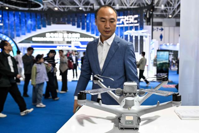 People visit the DJI booth during the Aero Asia 2025 in Zhuhai, in southern China's Guangdong province on November 29, 2025. Aero Asia 2025 is an international aviation and aerospace exhibition that runs between November 27 and 30. (Photo by Hector RETAMAL / AFP)