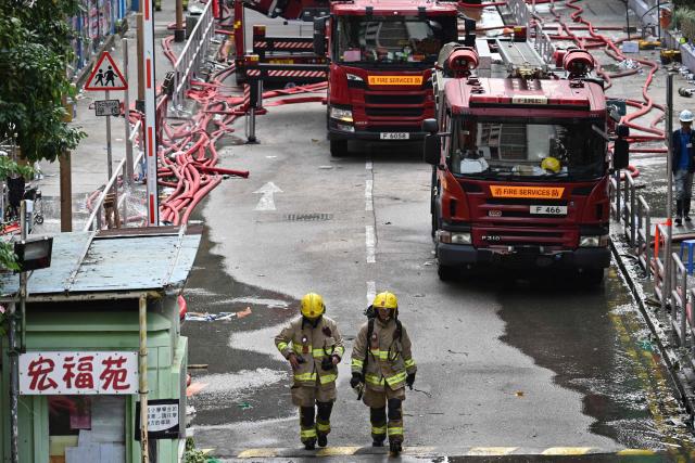 Firefighters work by the housing blocks of Wang Fuk Court in the aftermath of the deadly November 26 fire, in Hong Kong on November 29, 2025.  (Photo by Philip FONG / AFP)