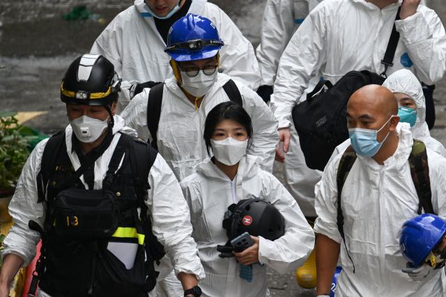 Police officers from the Disaster Victim Identification Unit (DVIU), dressed in white-coloured full-body protective gear, are seen near the housing blocks of Wang Fuk Court in the aftermath of the deadly November 26 fire, in Hong Kong on November 29, 2025.  (Photo by Philip FONG / AFP)