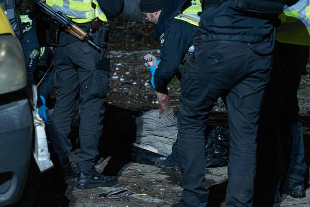 EDITORS NOTE: Graphic content / Police examine a body of a local resident outside a damaged residential building following a drone attack to Kyiv on November 29, 2025, amid the Russian invasion in Ukraine. A Russian drone attack targeted the Ukrainian capital in the early hours of November 29, killing one person and wounding seven, authorities in Kyiv said. (Photo by Anton SHTUKA / AFP)