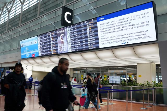 A bulletin board at the All Nippon Airways (ANA) check-in lobby shows a notice that a software upgrade was required for the airline's Airbus A321/A320 aircraft, which would result in delays and cancellations of flights, at Haneda Airport in Tokyo on November 29, 2025. Several airlines announced delayed or cancelled flights following an Airbus alert that up to 6,000 operational A320 family of aircraft may require upgrades. (Photo by Kazuhiro NOGI / AFP)