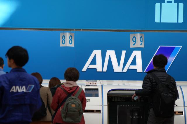 Passengers check in their luggage at the ANA baggage check-in counter at Haneda Airport in Tokyo on November 29, 2025. Several airlines announced delayed or cancelled flights following an Airbus alert that up to 6,000 operational A320 family of aircraft may require upgrades. (Photo by Kazuhiro NOGI / AFP)