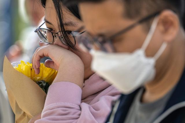 People gather to offer flowers outside the Wang Fuk Court in the aftermath of the deadly November 26 fire in Hong Kong's Tai Po district on November 29, 2025. An outpouring of grief was set to sweep Hong Kong on November 29 as an official, three-day mourning period began with a moment of silence for the 128 people killed in one of the city's deadliest fires. (Photo by Philip FONG / AFP)
