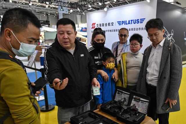 A drone vendor (center-L) sells drones during the Aero Asia 2025 in Zhuhai, in southern China's Guangdong province on November 29, 2025. Aero Asia 2025 is an international aviation and aerospace exhibition that runs between November 27 and 30. (Photo by Hector RETAMAL / AFP)