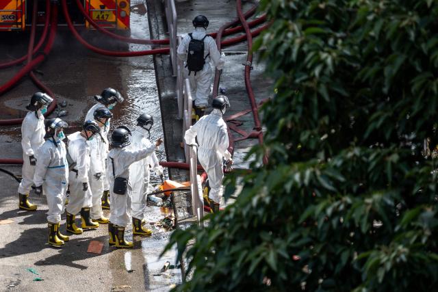 Police officers from the Disaster Victim Identification Unit (DVIU), dressed in white-coloured full-body protective gear, walk at the Wang Fuk Court in the aftermath of the deadly November 26 fire in Hong Kong's Tai Po district on November 29, 2025. An outpouring of grief was set to sweep Hong Kong on November 29 as an official, three-day mourning period began with a moment of silence for the 128 people killed in one of the city's deadliest fires. (Photo by Philip FONG / AFP)