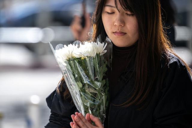 A woman prays before offering flowers outside the Wang Fuk Court in the aftermath of the deadly November 26 fire in Hong Kong's Tai Po district on November 29, 2025. An outpouring of grief was set to sweep Hong Kong on November 29 as an official, three-day mourning period began with a moment of silence for the 128 people killed in one of the city's deadliest fires. (Photo by Philip FONG / AFP)