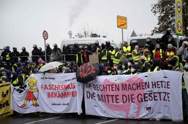 Police stand behind demonstrators holding banners against farright politics during a protest against a two-day convention of far-right Alternative for Germany (AfD) party to establish its new youth organisation in Giessen, western Germany, on November 29, 2025. During the convention, Germany's AfD plans to establish its new youth organisation, to draft the organisation's statutes and elect its new leadership. The AfD's former youth organisation, Junge Alternative (Young Alternative), dissolved in spring 2025 after the party separated from it. Massive counter-protests from politicians and civil society have already been announced. The city announced that it intended to cordon off the entire area around the AfD event venue due to police security concerns. The anti-AfD protests are to be moved to the other side of the Lahn River. (Photo by Sascha Schuermann / AFP)