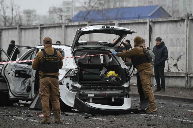 Law enforcement officers work next to a destroyed car at the site of a drone attack in Kyiv on November 29, 2025, amid the Russian invasion in Ukraine. A Russian drone attack targeted the Ukrainian capital in the early hours of November 29, 2025, killing one person and wounding seven, authorities in Kyiv said. (Photo by Genya SAVILOV / AFP)
