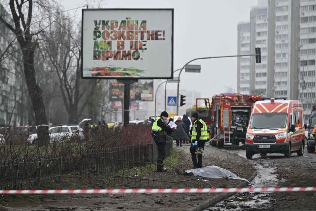 EDITORS NOTE: Graphic content / Law enforcement officers stand next to the covered body of a killed person in front of a damaged residential building following a drone attack in Kyiv on November 29, 2025, amid the Russian invasion in Ukraine. A Russian drone attack targeted the Ukrainian capital in the early hours of November 29, 2025, killing one person and wounding seven, authorities in Kyiv said. (Photo by Genya SAVILOV / AFP)