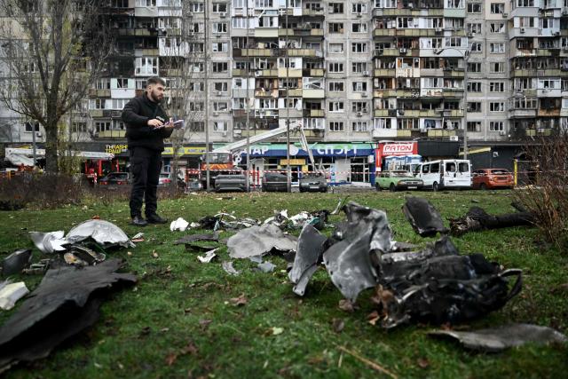 A law enforcement officer inspects debris of an unidentified object in front of a damaged residential building following an air attack in Kyiv on November 29, 2025, amid the Russian invasion in Ukraine. A Russian drone attack targeted the Ukrainian capital in the early hours of November 29, 2025, killing one person and wounding seven, authorities in Kyiv said. (Photo by Genya SAVILOV / AFP)