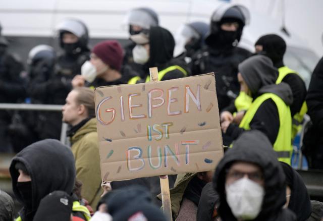Police stand next to demonstrators holding a placard reading "Giessen is colourful" against farright politics during a protest against a two-day convention of far-right Alternative for Germany (AfD) party to establish its new youth organisation in Giessen, western Germany, on November 29, 2025. During the convention, Germany's AfD plans to establish its new youth organisation, to draft the organisation's statutes and elect its new leadership. The AfD's former youth organisation, Junge Alternative (Young Alternative), dissolved in spring 2025 after the party separated from it. Massive counter-protests from politicians and civil society have already been announced. The city announced that it intended to cordon off the entire area around the AfD event venue due to police security concerns. The anti-AfD protests are to be moved to the other side of the Lahn River. (Photo by Sascha Schuermann / AFP)