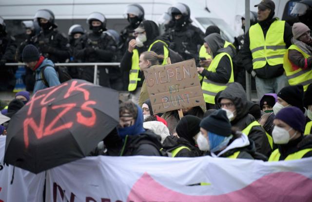 Police stand next to demonstrators holding a placard reading "Giessen is colourful" against farright politics during a protest against a two-day convention of far-right Alternative for Germany (AfD) party to establish its new youth organisation in Giessen, western Germany, on November 29, 2025. During the convention, Germany's AfD plans to establish its new youth organisation, to draft the organisation's statutes and elect its new leadership. The AfD's former youth organisation, Junge Alternative (Young Alternative), dissolved in spring 2025 after the party separated from it. Massive counter-protests from politicians and civil society have already been announced. The city announced that it intended to cordon off the entire area around the AfD event venue due to police security concerns. The anti-AfD protests are to be moved to the other side of the Lahn River. (Photo by Sascha Schuermann / AFP)