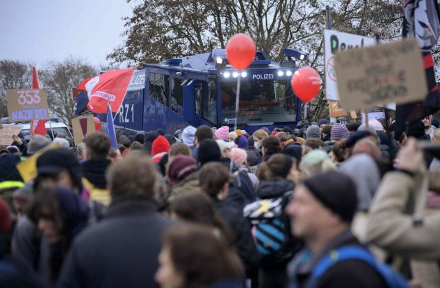 An armoured police vehicle stands next to demonstrators holding placards against farright politics during a protest against a two-day convention of far-right Alternative for Germany (AfD) party to establish its new youth organisation in Giessen, western Germany, on November 29, 2025. During the convention, Germany's AfD plans to establish its new youth organisation, to draft the organisation's statutes and elect its new leadership. The AfD's former youth organisation, Junge Alternative (Young Alternative), dissolved in spring 2025 after the party separated from it. Massive counter-protests from politicians and civil society have already been announced. The city announced that it intended to cordon off the entire area around the AfD event venue due to police security concerns. The anti-AfD protests are to be moved to the other side of the Lahn River. (Photo by Sascha Schuermann / AFP)