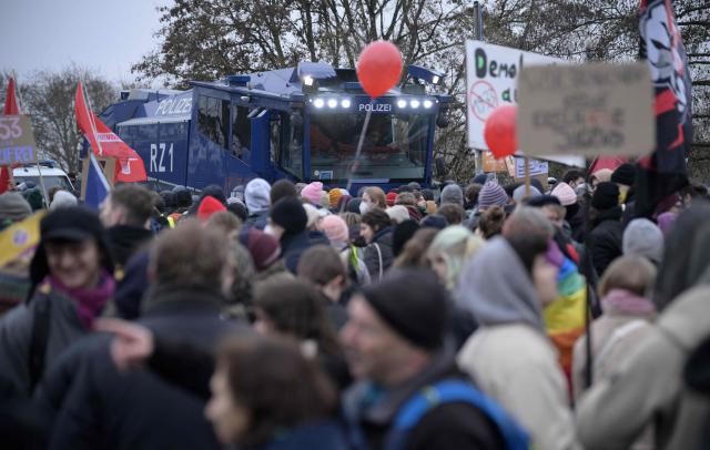 An armoured police vehicle stands next to demonstrators against farright politics during a protest against a two-day convention of far-right Alternative for Germany (AfD) party to establish its new youth organisation in Giessen, western Germany, on November 29, 2025. During the convention, Germany's AfD plans to establish its new youth organisation, to draft the organisation's statutes and elect its new leadership. The AfD's former youth organisation, Junge Alternative (Young Alternative), dissolved in spring 2025 after the party separated from it. Massive counter-protests from politicians and civil society have already been announced. The city announced that it intended to cordon off the entire area around the AfD event venue due to police security concerns. The anti-AfD protests are to be moved to the other side of the Lahn River. (Photo by Sascha Schuermann / AFP)