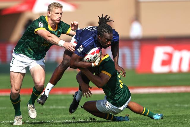 France's #75 Ali Dabo (C) is tackled by South Africa's #02 Ryan Oosthuize (L) and #12 Shilton van Wyk, during the men's Dubai Sevens Rugby Union match between South Africa and France, at the The Sevens Stadium in Dubai on November 29, 2025. (Photo by Fadel SENNA / AFP)
