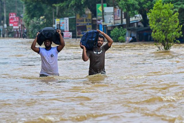 People carrying belongings wade through a flooded road after heavy rainfall in Kaduwela on the outskirts of Colombo on November 29, 2025. Sri Lanka made an appeal for international assistance on November 29 as the death toll from heavy rains and floods triggered by Cyclone Ditwah rose to 123, with another 130 reported missing. (Photo by Ishara S. KODIKARA / AFP)
