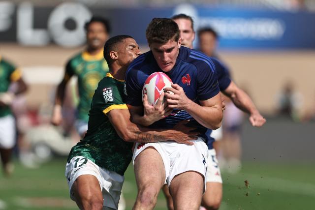 South Africa's #12 Shilton van Wyk (L) tackles Frances #28 Josselin Bouhie, during the men's Dubai Sevens Rugby Union match between South Africa and France, at the The Sevens Stadium in Dubai on November 29, 2025. (Photo by Fadel SENNA / AFP)
