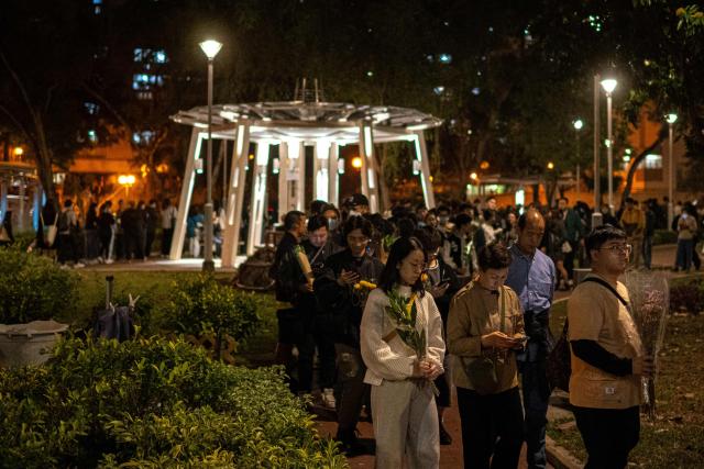 People line up to offer flowers outside the Wang Fuk Court in the aftermath of the deadly November 26 fire in Hong Kong's Tai Po district on November 29, 2025. An outpouring of grief was set to sweep Hong Kong on November 29 as an official, three-day mourning period began with a moment of silence for the 128 people killed in one of the city's deadliest fires. (Photo by Philip FONG / AFP)