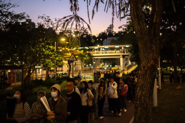 People line up to offer flowers outside the Wang Fuk Court in the aftermath of the deadly November 26 fire in Hong Kong's Tai Po district on November 29, 2025. An outpouring of grief was set to sweep Hong Kong on November 29 as an official, three-day mourning period began with a moment of silence for the 128 people killed in one of the city's deadliest fires. (Photo by Philip FONG / AFP)