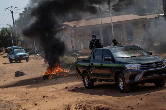 Guinea Bissau security forces patrol cars drive near burning tyres in the area of incidents with protestors in Bissau on Novmeber 29, 2025. (Photo by Patrick MEINHARDT / AFP)