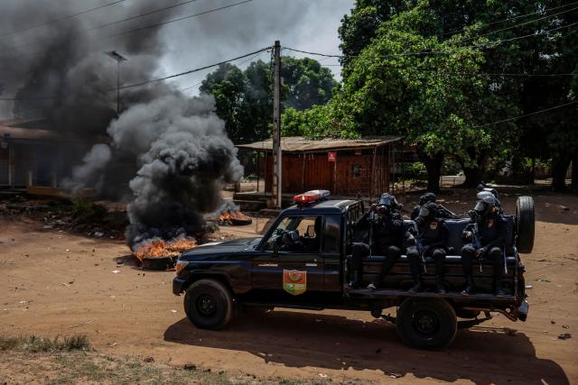 TOPSHOT - A Guinea Bissau Police patrol car speeds past burning tyres during incidents in Bissau on Novmeber 29, 2025. (Photo by Patrick MEINHARDT / AFP)
