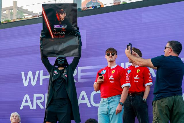 A fan wearing a Darth Vader mask holds a poster depicting Red Bull Racing's Dutch driver Max Verstappen before the start of the sprint race ahead of the Formula One Qatar Grand Prix at the Lusail International Circuit in Lusail on November 29, 2025. (Photo by Karim JAAFAR / AFP)