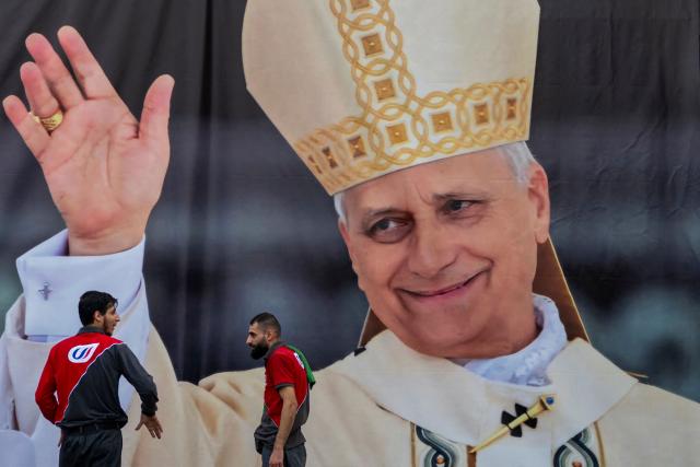 TOPSHOT - Gas station employees set a large banner of Pope Leo XIV in Beirut on November 29, 2025. Militant group Hezbollah on November 29 urged Pope Leo XIV to reject Israeli "injustice and aggression" against Lebanon, in a message to the pontiff who arrives in Beirut this weekend. (Photo by Jewel SAMAD / AFP)