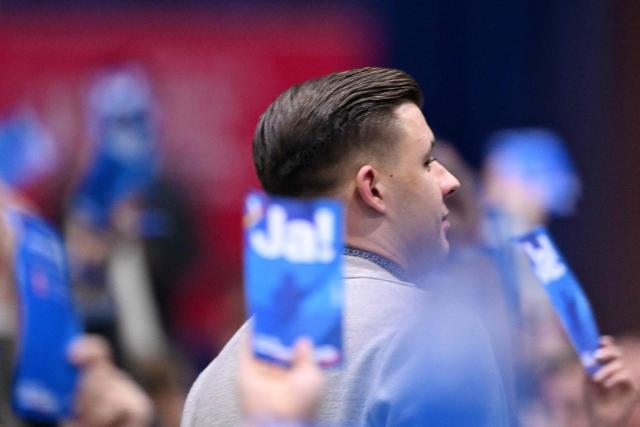 Jean-Pascal Hohm, an AfD state lawmaker from the eastern German state of Brandenburg, is seen amid delegates holding up voting cards reading 'Yes' during a two-day convention of far-right Alternative for Germany (AfD) party to establish its new youth organisation at the exhibition halls in Giessen, western Germany, on November 29, 2025. (Photo by Kirill KUDRYAVTSEV / AFP)