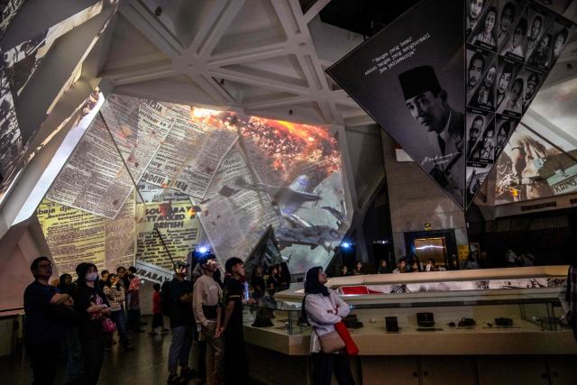 Visitors watch an immersive video depicting the Battle of Surabaya, which took place in November 1945 between Indonesian nationalists against British and British Indian forces for the re-imposition of Dutch colonial rule following the end of World War II, during the 'Night at the Museum 2025' event at the 10 November Museum in Surabaya on November 29, 2025. (Photo by Juni KRISWANTO / AFP)