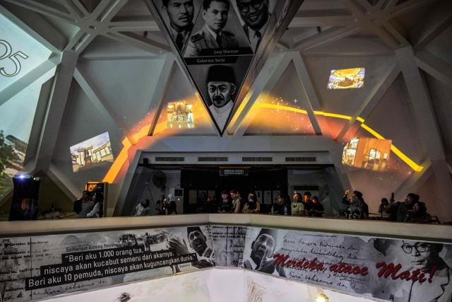 Visitors watch an immersive video depicting the Battle of Surabaya, which took place in November 1945 between Indonesian nationalists against British and British Indian forces for the re-imposition of Dutch colonial rule following the end of World War II, during the 'Night at the Museum 2025' event at the 10 November Museum in Surabaya on November 29, 2025. (Photo by Juni KRISWANTO / AFP)