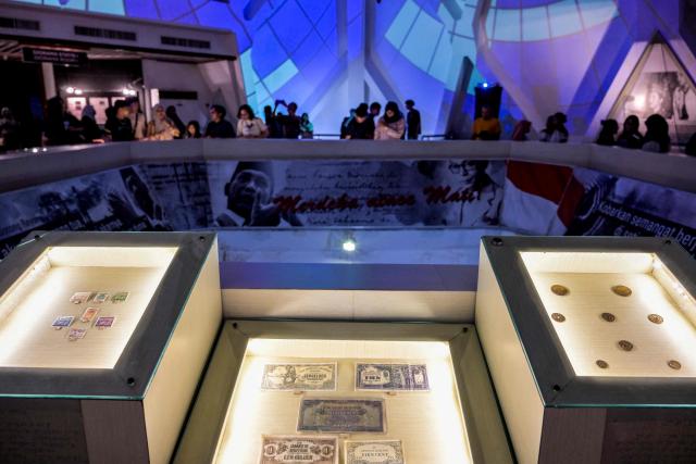 Old Indonesian postage stamps and Japanese currency notes are seen as visitors watch an immersive video depicting the Battle of Surabaya, which took place in November 1945 between Indonesian nationalists against British and British Indian forces for the re-imposition of Dutch colonial rule following the end of World War II, during the 'Night at the Museum 2025' event at the 10 November Museum in Surabaya on November 29, 2025. (Photo by Juni KRISWANTO / AFP)
