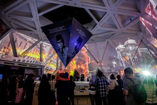 Visitors watch an immersive video depicting the Battle of Surabaya, which took place in November 1945 between Indonesian nationalists against British and British Indian forces for the re-imposition of Dutch colonial rule following the end of World War II, during the 'Night at the Museum 2025' event at the 10 November Museum in Surabaya on November 29, 2025. (Photo by Juni KRISWANTO / AFP)
