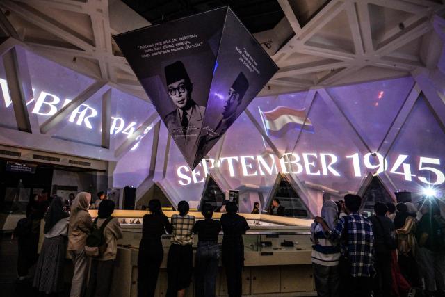 Visitors watch an immersive video depicting the Battle of Surabaya, which took place in November 1945 between Indonesian nationalists against British and British Indian forces for the re-imposition of Dutch colonial rule following the end of World War II, during the 'Night at the Museum 2025' event at the 10 November Museum in Surabaya on November 29, 2025. (Photo by Juni KRISWANTO / AFP)