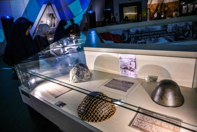 Visitors look at military equipment seized by Indonesia from Japan, British India and Dutch forces amid the Battle of Surabaya, which took place in November 1945 between Indonesian nationalists against British and British Indian forces for the re-imposition of Dutch colonial rule following the end of World War II, during the 'Night at the Museum 2025' event at the 10 November Museum in Surabaya on November 29, 2025. (Photo by Juni KRISWANTO / AFP)