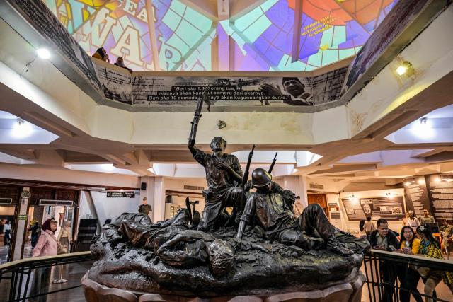 Visitors look at a sculpture depicting the Battle of Surabaya, which took place in November 1945 between Indonesian nationalists against British and British Indian forces for the re-imposition of Dutch colonial rule following the end of World War II, during the 'Night at the Museum 2025' event at the 10 November Museum in Surabaya on November 29, 2025. (Photo by Juni KRISWANTO / AFP)