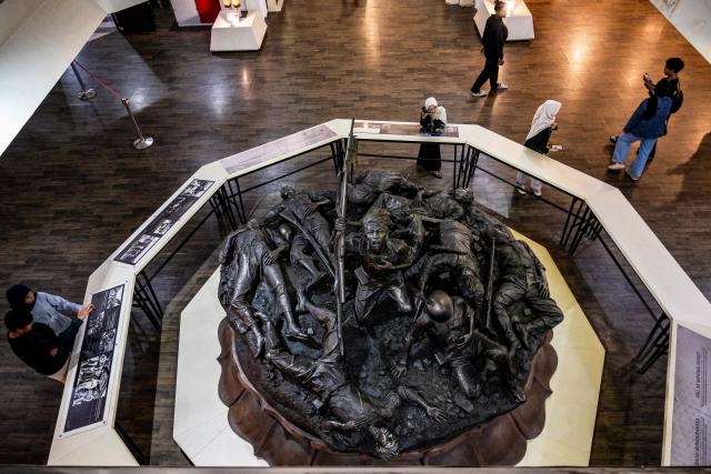 Visitors look at a sculpture depicting the Battle of Surabaya, which took place in November 1945 between Indonesian nationalists against British and British Indian forces for the re-imposition of Dutch colonial rule following the end of World War II, during the 'Night at the Museum 2025' event at the 10 November Museum in Surabaya on November 29, 2025. (Photo by Juni KRISWANTO / AFP)