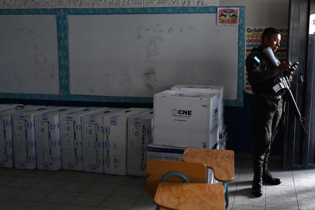 A soldier uses a mobile phone as he custodies boxes with electoral material at a polling station in Tegucigalpa, on November 29, 2025, a day before the presidential election. (Photo by MARVIN RECINOS / AFP)
