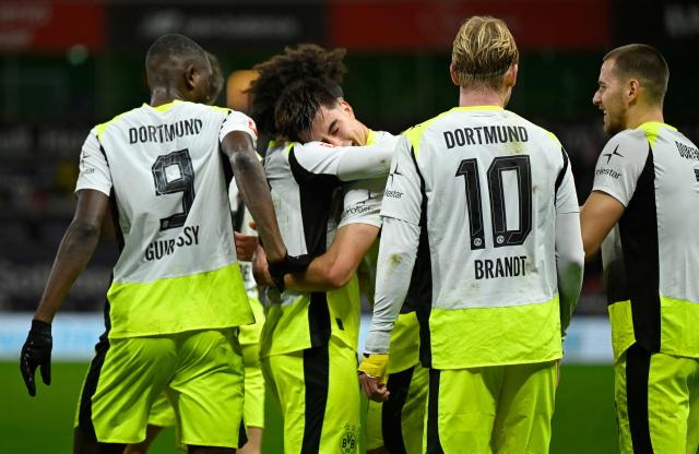Dortmund's Argentinian defender #28 Aaron Anselmino (C) celebrates his 0-1 with team mates during the German first division Bundesliga football match between Bayer 04 Leverkusen and Borussia Dortmund in Leverkusen, western Germany, on November 29, 2025. (Photo by INA FASSBENDER / AFP) / DFL REGULATIONS PROHIBIT ANY USE OF PHOTOGRAPHS AS IMAGE SEQUENCES AND/OR QUASI-VIDEO