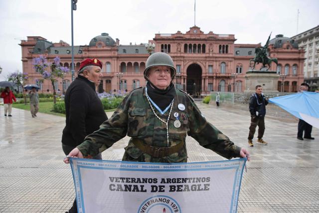 A defender of convicted perpetrators of genocide holding a flag that reads “Argentine Veterans" demonstrates in Plaza de Mayo in Buenos Aires, on November 29, 2025, wearing a black scarf instead of the traditional white one of the Human Rights activists Madres and Abuelas de Plaza de Mayo. (Photo by Emiliano Lasalvia / AFP)
