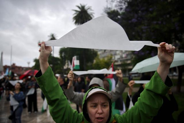 Demonstrators hold white scarves, worn by the Mothers of Plaza de Mayo to symbolize the diapers once used by their disappeared children, during a pro-Palestinian march in Buenos Aires, on November 29, 2025. (Photo by Emiliano Lasalvia / AFP)