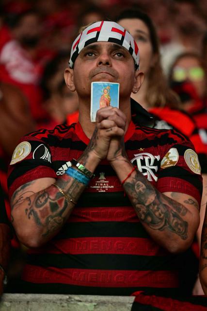 A Flamengo fan prays while watching the all Brazilian Copa Libertadores final football match between Palmeiras and Flamengo on screens at the Maracana stadium in Rio de Janeiro, Brazil, on November 29, 2025. (Photo by Pablo PORCIUNCULA / AFP)
