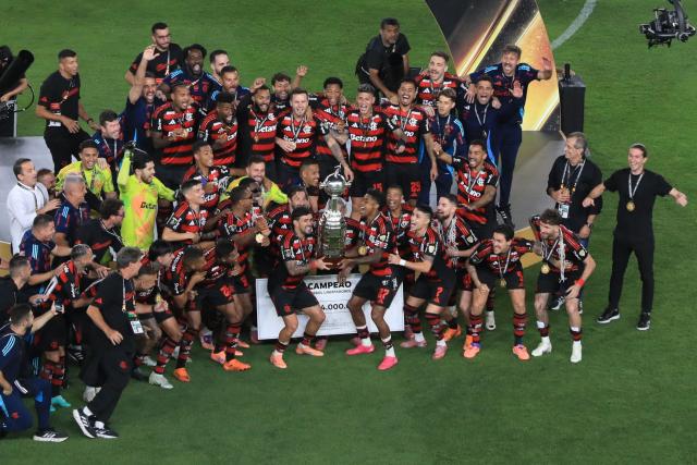 Flamengo's forward #27 Bruno Henrique (R) and Uruguayan midfielder #10 Giorgian de Arrascaeta (L) lift the the trophy with teammates after winning the all Brazilian Copa Libertadores final football match between Palmeiras and Flamengo at Monumental 'U' Marathon stadium in Lima on November 29, 2025. (Photo by Connie FRANCE / AFP)