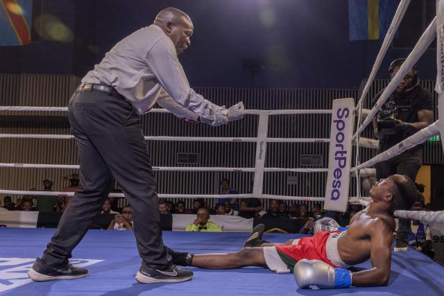 Referee Charles Juma (L) gives the countdown to Kenya's boxer Justus Ndegwa after being knocked down by unseen Kenya's boxer Michael Oduor during their men's Super Welterweight boxing title bout at the Edge Convention Centre, in Nairobi on November 30, 2025. (Photo by SIMON MAINA / AFP)