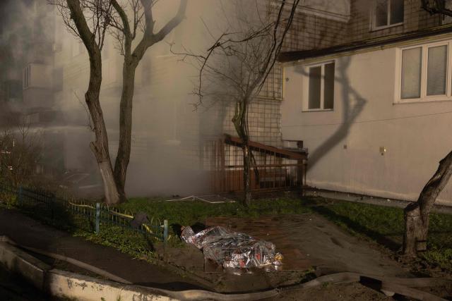 A covered body of a victim lays next to a residential building on fire following a Russian drone attack on the city of Vyshhorod, in the Kyiv region early on November 30, 2025, amid the Russian invasion of Ukraine. (Photo by Roman PILIPEY / AFP)