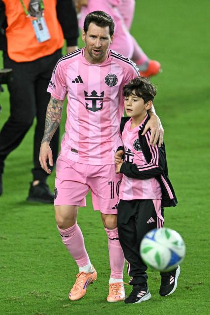 Inter Miami's Argentine forward #10 Lionel Messi (L) greets one of his children as he celebrates his team's victory in the Major League Soccer (MLS) Eastern Conference final football match between Inter Miami and New York City FC at Chase Stadium in Fort Lauderdale, Florida on November 29, 2025. Lionel Messi and Inter Miami reached the MLS Cup final for the first time on November 29, 2025 after a 5-1 thrashing of New York City FC in the Eastern Conference playoffs. (Photo by CHANDAN KHANNA / AFP)