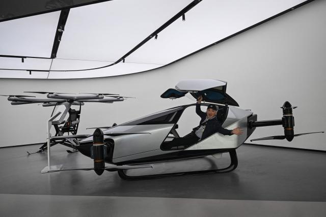 (FILES) A journalist sits in Xpeng's flying car Traveller X2 during a showroom tour in Guangzhou, in southern China's Guangdong province on November 5, 2025. Globally, technical and regulatory challenges have prevented the much-hyped flying car sector from getting off the ground. But Chinese companies are building on rapid development of drones and electric vehicles in the world's second largest economy, while harnessing government support for the futuristic inventions. (Photo by Jade GAO / AFP) / To go with AFP story China-economy-technology-automobile-drone, FOCUS by Luna Lin