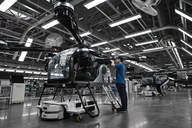 (FILES) Employees work on the assembly line for the electric flying car “Land Aircraft Carrier” at a factory of Xpeng's subsidiary Aridge in Guangzhou, in southern China's Guangdong province on November 6, 2025. Globally, technical and regulatory challenges have prevented the much-hyped flying car sector from getting off the ground. But Chinese companies are building on rapid development of drones and electric vehicles in the world's second largest economy, while harnessing government support for the futuristic inventions. (Photo by Jade GAO / AFP) / To go with AFP story China-economy-technology-automobile-drone, FOCUS by Luna Lin