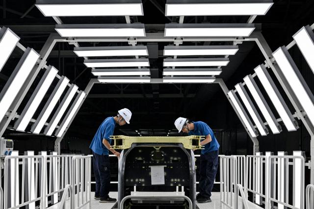 (FILES) Employees work on the production line for the electric flying car “Land Aircraft Carrier” at a factory of Xpeng's subsidiary Aridge in Guangzhou, in southern China's Guangdong province on November 6, 2025. Globally, technical and regulatory challenges have prevented the much-hyped flying car sector from getting off the ground. But Chinese companies are building on rapid development of drones and electric vehicles in the world's second largest economy, while harnessing government support for the futuristic inventions. (Photo by Jade GAO / AFP) / To go with AFP story China-economy-technology-automobile-drone, FOCUS by Luna Lin